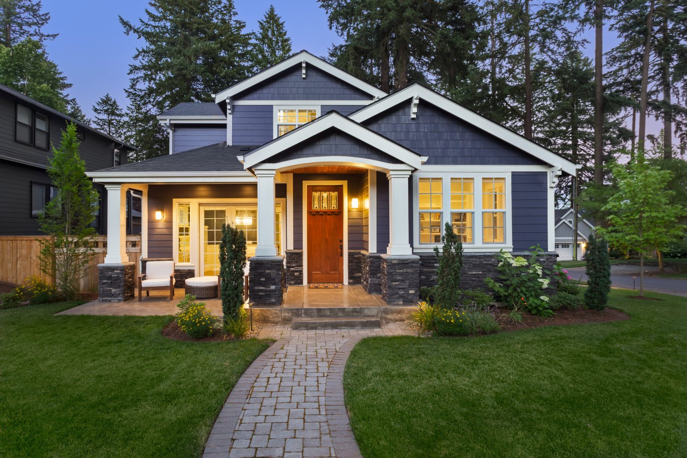 Craftsman-style home with exterior and porch lighting at dusk