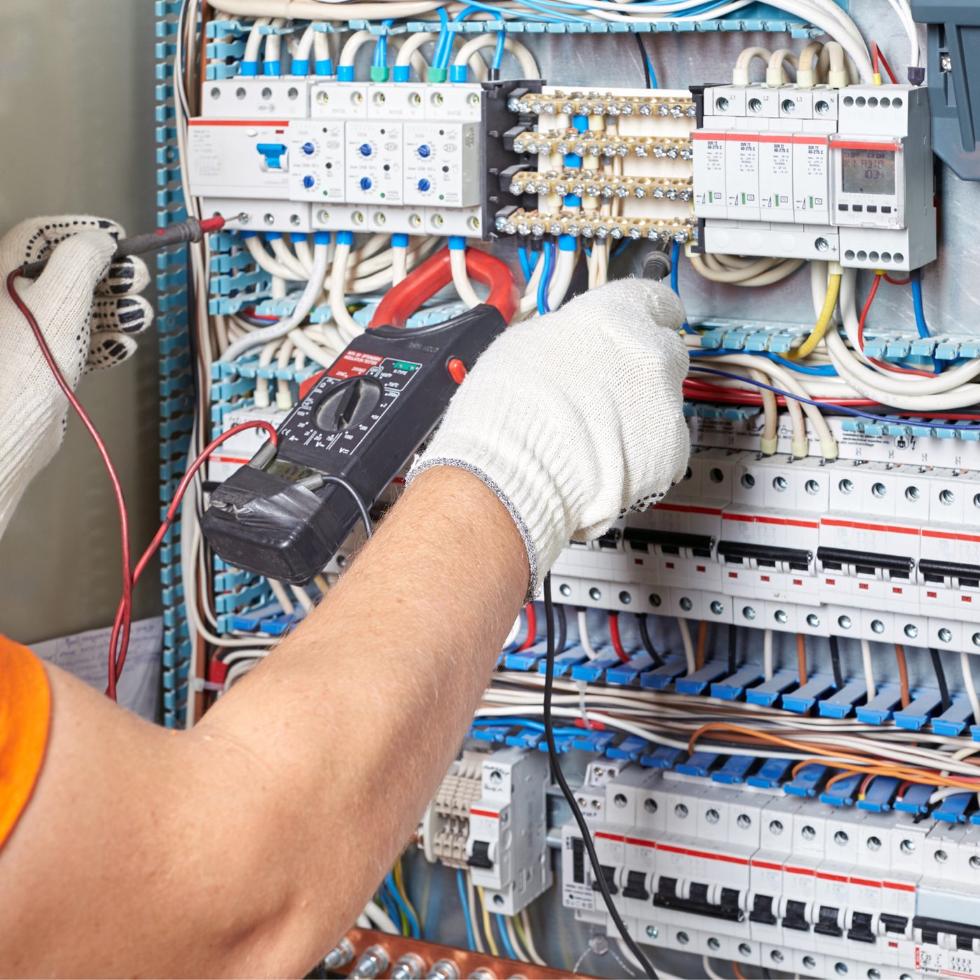 Electrician measuring current in an industrial control panel with a clamp meter