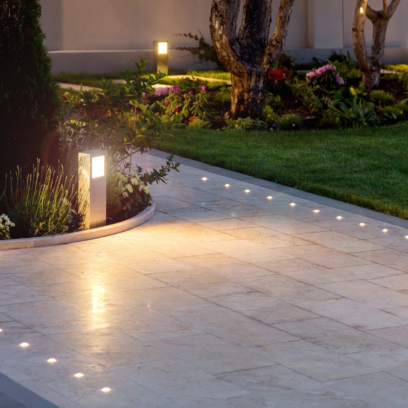 Walkway and garden beds lit by landscape lighting at night