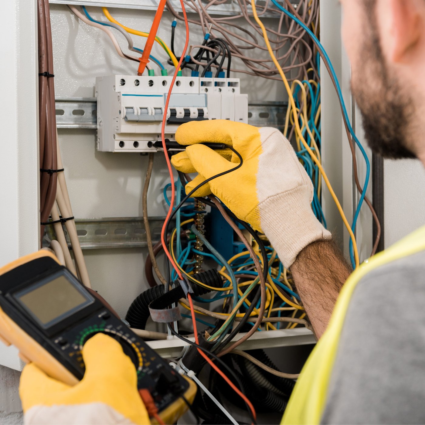 Electrician checking a breaker panel with a multimeter